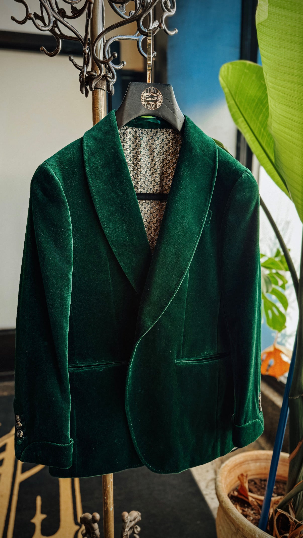 Green velvet blazer on a mannequin against a blurred indoor background